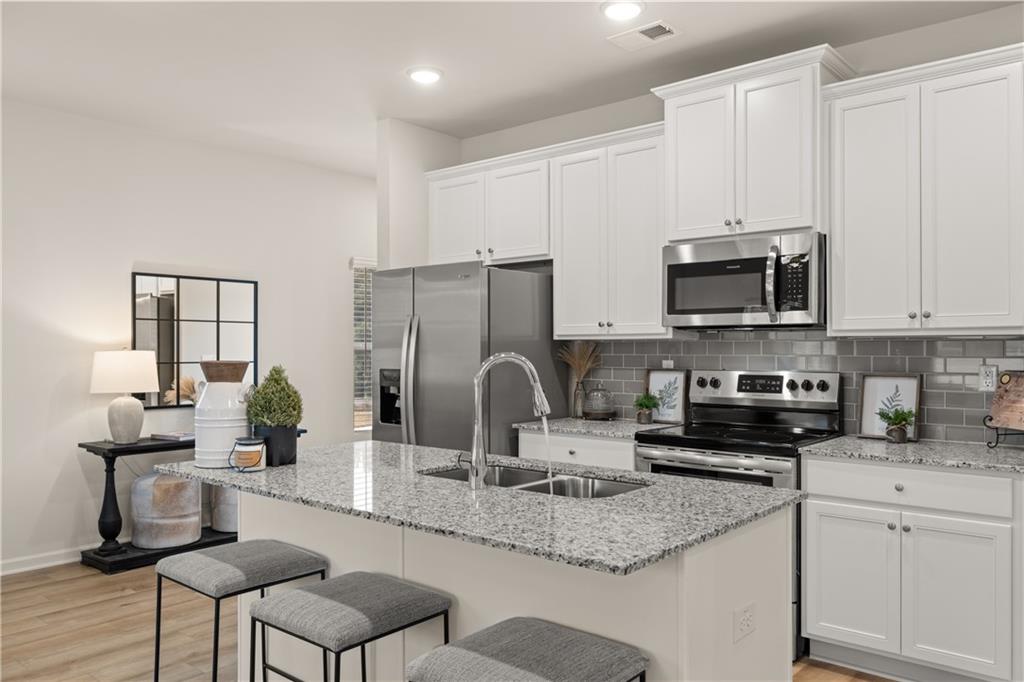 1035 Merritt Drive, Unit 94 Villa Rica, GA 30180 - Photo 5 of 49 a kitchen with kitchen island granite countertop a sink and a stove top oven with white cabinets
