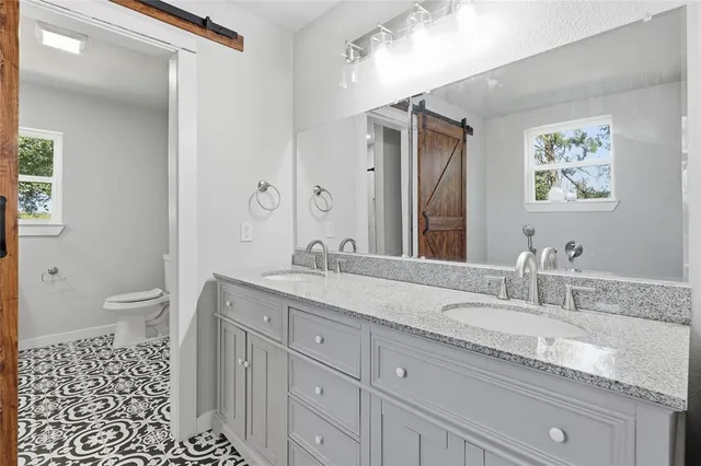 a bathroom with a granite countertop sink mirror and toilet