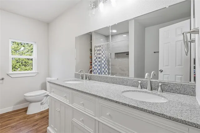 a bathroom with a granite countertop sink a toilet a mirror and a window