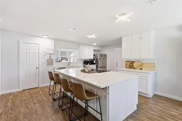 a kitchen with stainless steel appliances a white table chairs and a refrigerator