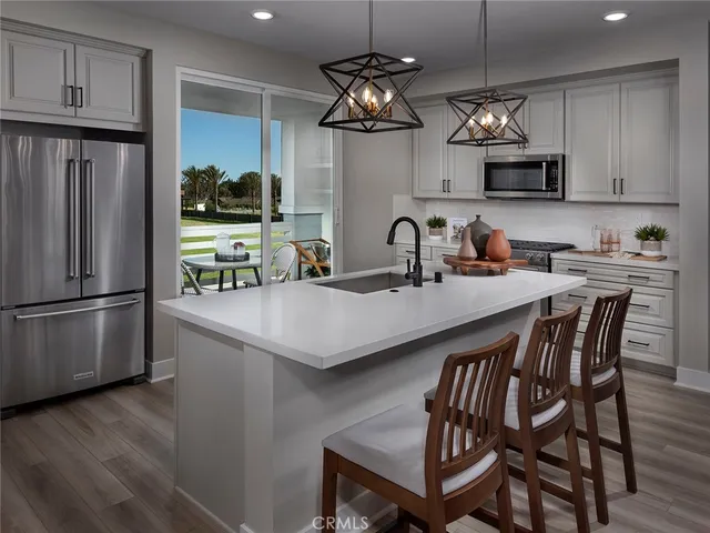 a kitchen with stainless steel appliances a table chairs refrigerator and microwave