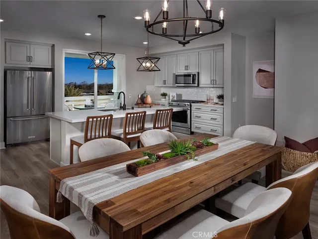 a kitchen with stainless steel appliances granite countertop a stove a refrigerator a kitchen island a dining table and chairs