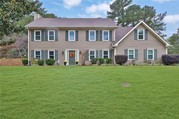 a front view of a house with a garden and trees