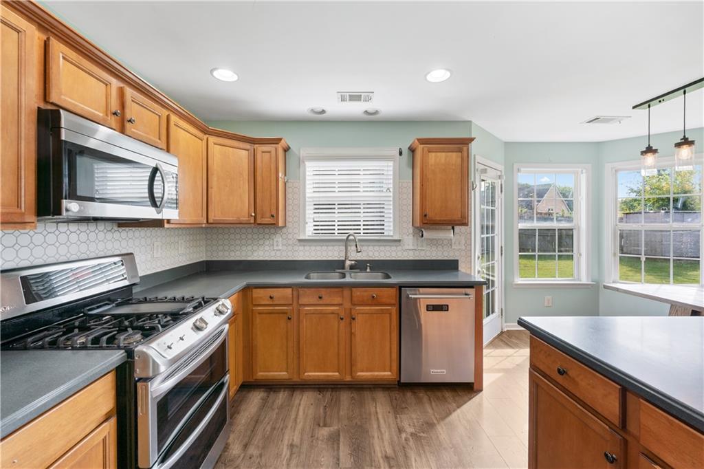 871 New Liberty Way Braselton, GA 30517 - Photo 9 of 47 a kitchen with stainless steel appliances granite countertop wooden cabinets stove top oven and sink