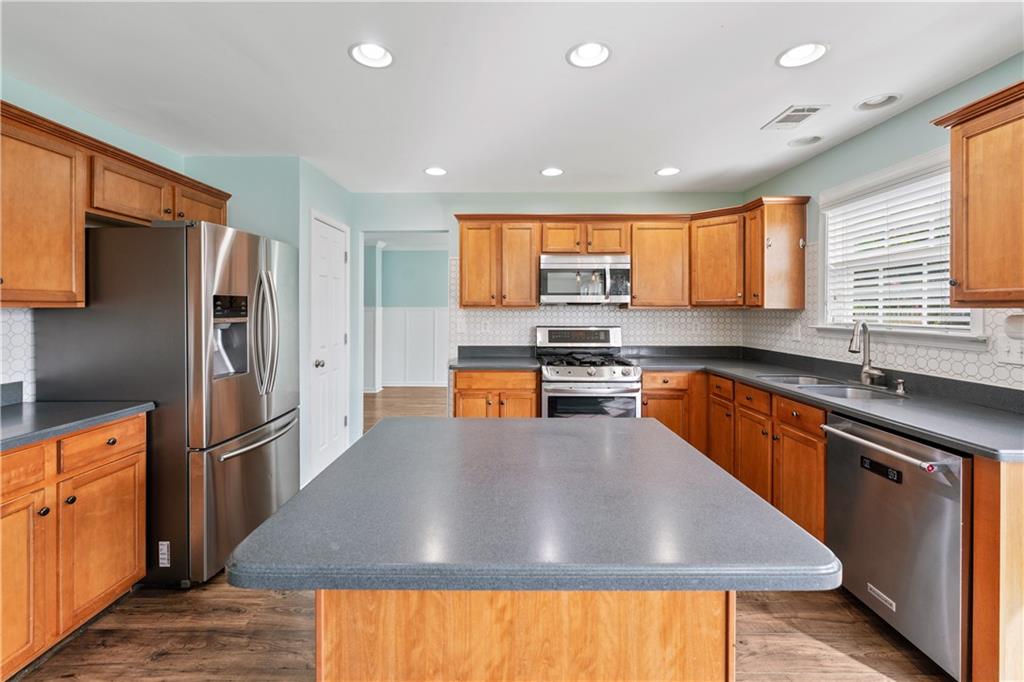 871 New Liberty Way Braselton, GA 30517 - Photo 10 of 47 a kitchen with stainless steel appliances granite countertop a refrigerator a sink dishwasher a stove and a sink with wooden floor