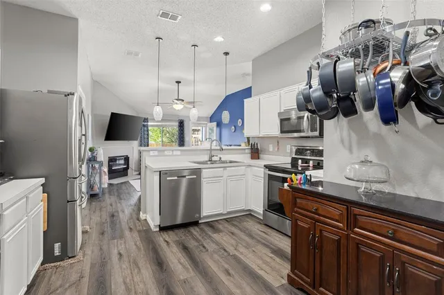 a kitchen with stainless steel appliances granite countertop a sink a stove and a wooden floors
