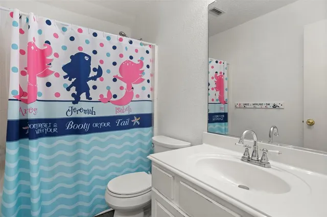 a bathroom with a sink a toilet and a shower curtain