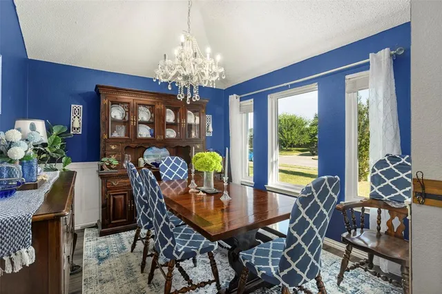 a view of a dining room with furniture a chandelier and large windows