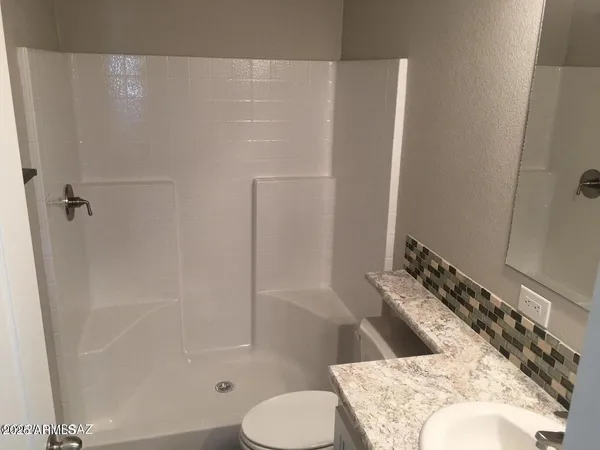 a bathroom with a granite countertop sink a toilet and a bathtub