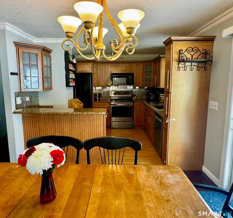 a kitchen with stainless steel appliances kitchen island granite countertop a table chairs in it and a window