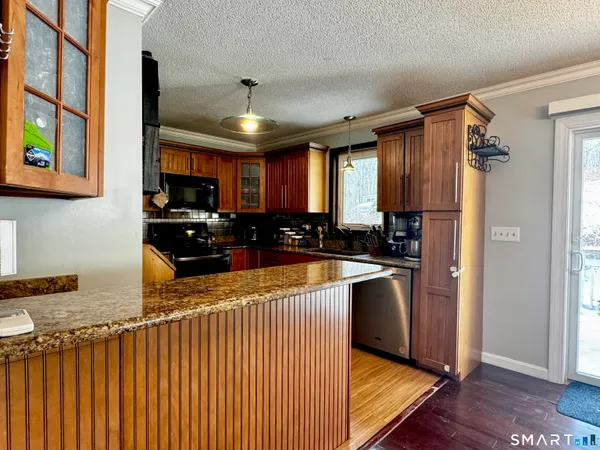 a kitchen with stainless steel appliances granite countertop a refrigerator a sink dishwasher a stove and wooden cabinets with wooden floor