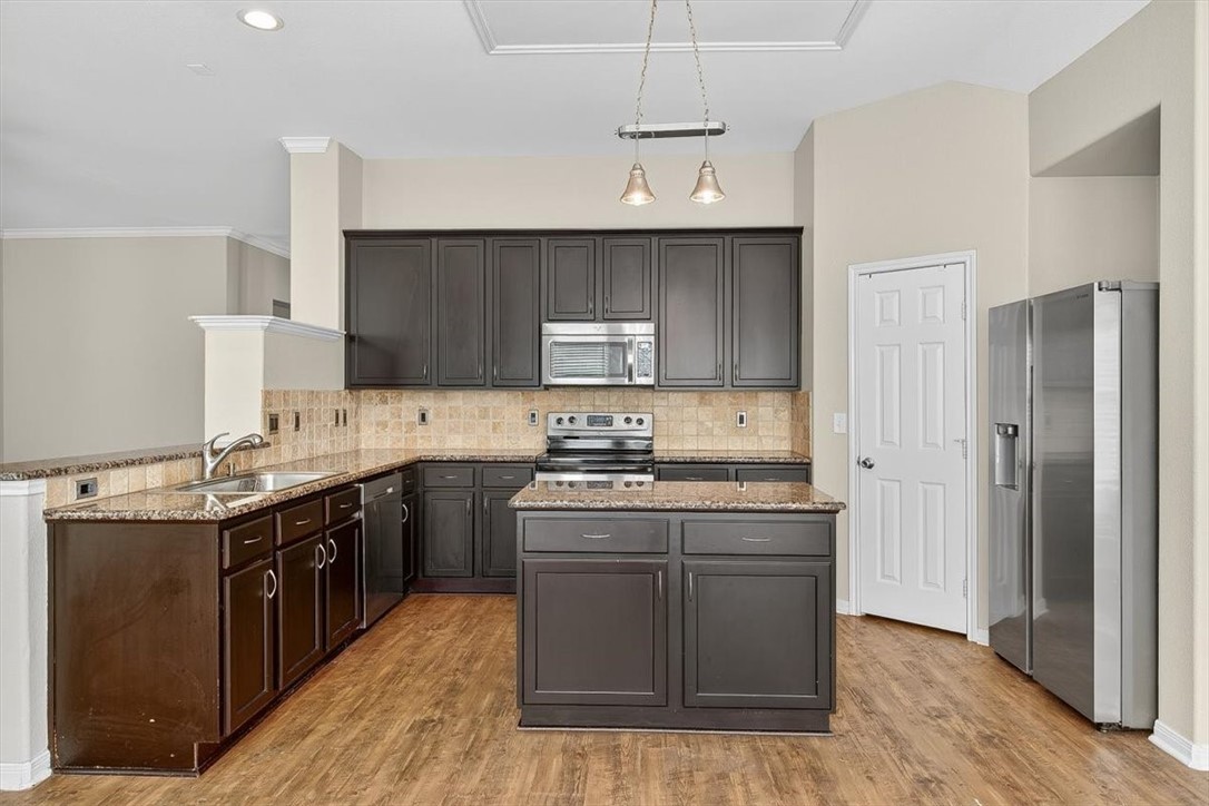7506 Exeter Corpus Christi, TX 78414 - Photo 13 of 40 a kitchen with stainless steel appliances granite countertop a stove a sink dishwasher a refrigerator and a oven with wooden floor