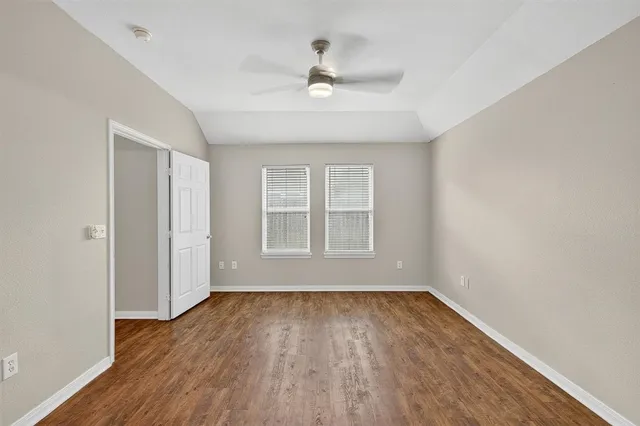 an empty room with wooden floor fan and windows