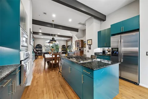 a kitchen with stainless steel appliances granite countertop a refrigerator a stove and a wooden floors