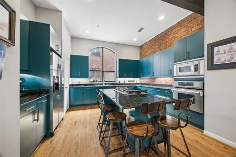 a kitchen with stainless steel appliances kitchen island granite countertop a table chairs in it and wooden floors