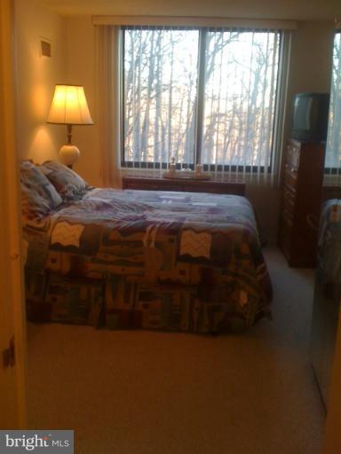 5225 Pooks Hill Road, Unit 406N Bethesda, MD 20814 - Photo 6 of 18 a bedroom with a bed lamp and a large window