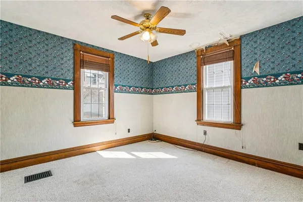 an empty room with windows and fan