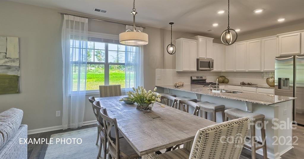 7200 Indigo Way Denver, NC 28037 - Photo 4 of 11 a kitchen with stainless steel appliances granite countertop a stove a kitchen island a table and chairs