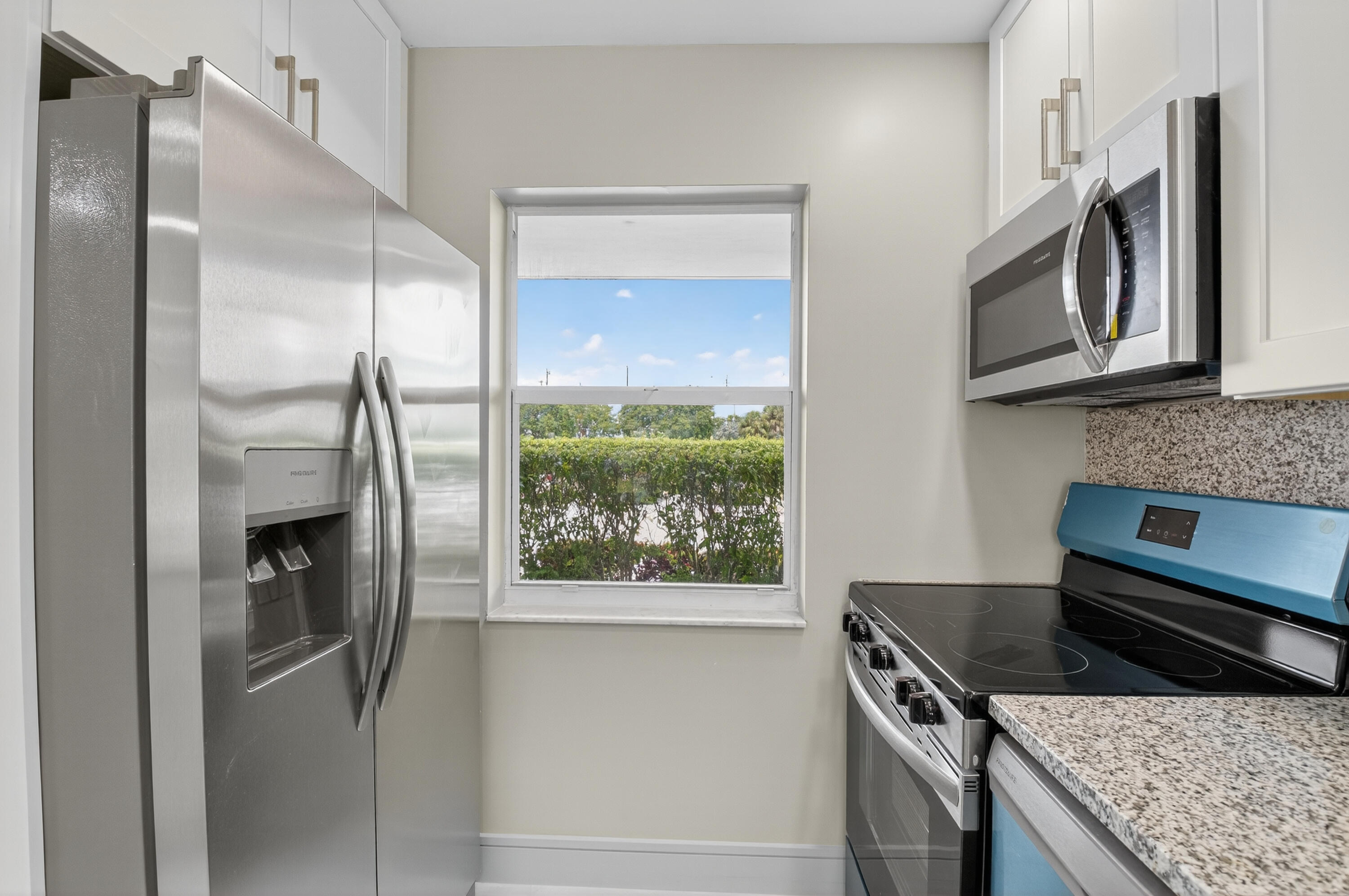 9880 Marina Boulevard, Unit 1509 Boca Raton, FL 33428 - Photo 8 of 43 a kitchen with stainless steel appliances granite countertop a refrigerator a stove and a sink with wooden floor