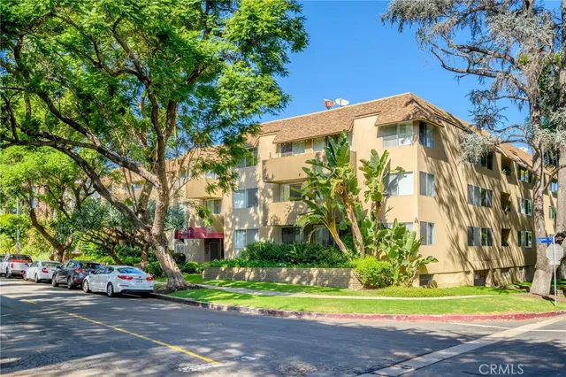 a front view of multi story residential apartment building with yard and green space