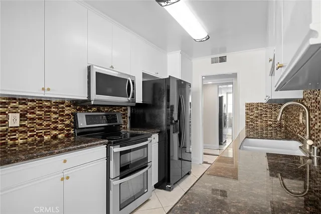 a kitchen with granite countertop a refrigerator and a stove top oven