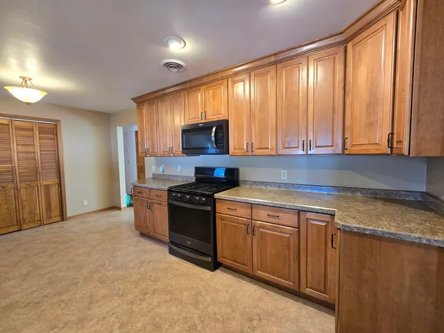 a kitchen with stainless steel appliances granite countertop a stove a sink and a microwave