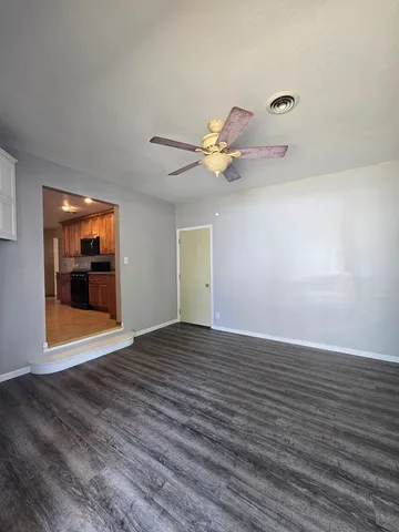 a view of an empty room with window and wooden floor