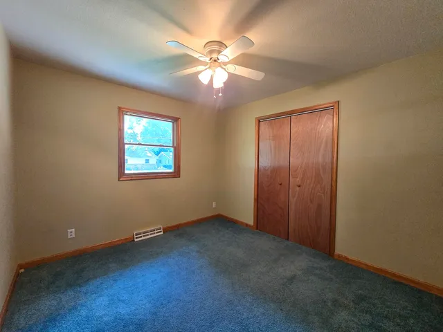 an empty room with windows and fan