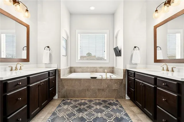 a spacious bathroom with a tub sink and mirror