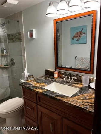 a bathroom with a granite countertop sink mirror vanity and toilet