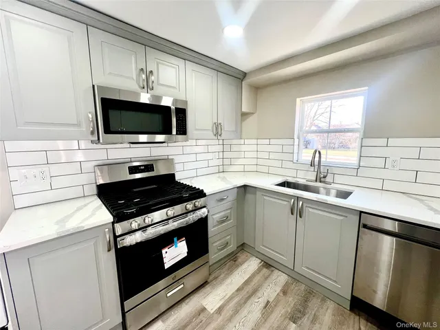 a kitchen with cabinets stainless steel appliances a sink and a window