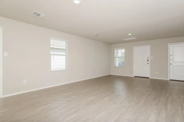an empty room with wooden floor and window