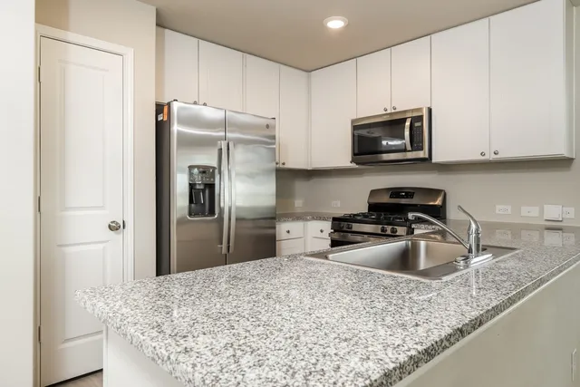 a kitchen with stainless steel appliances granite countertop a sink a refrigerator and a granite counter tops