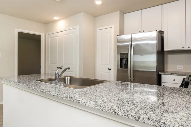a kitchen with granite countertop a refrigerator and a sink