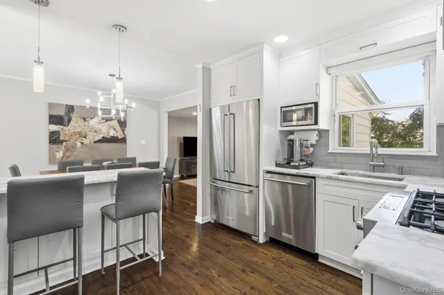 a kitchen with stainless steel appliances a dining table chairs refrigerator and sink