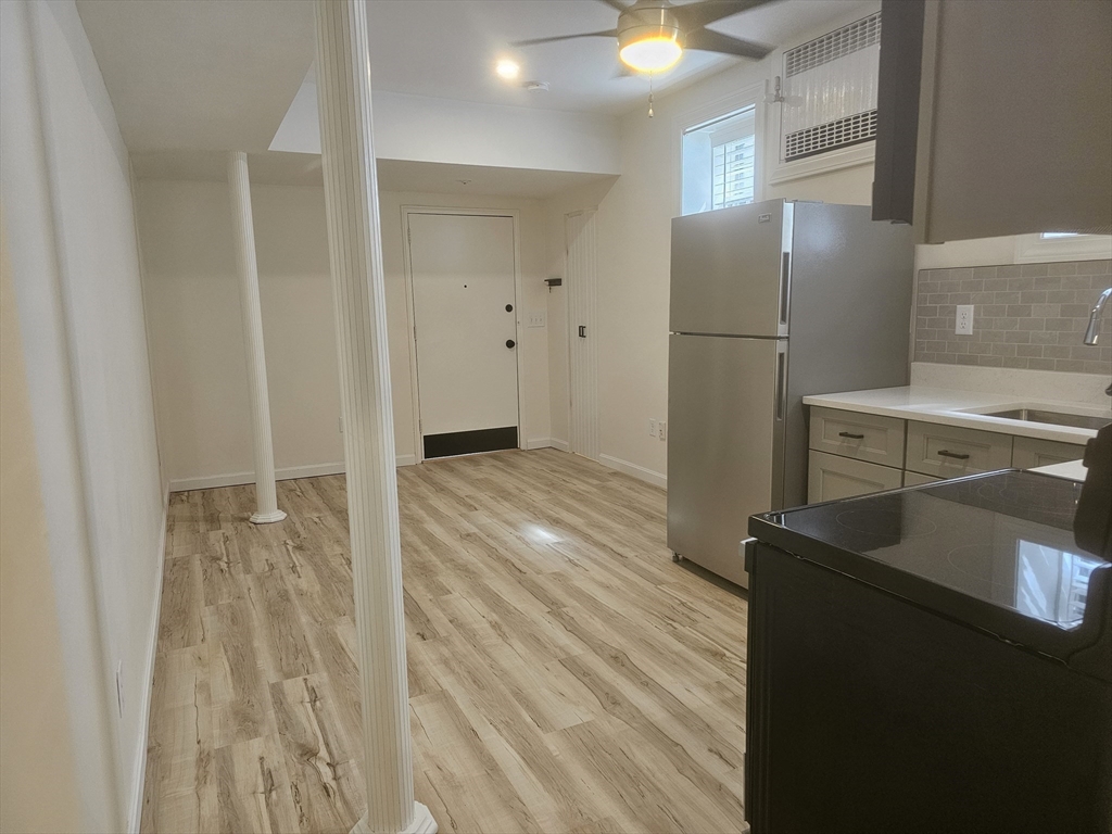 60 Elm Street, Unit 2A Worcester, MA 01609 - Photo 7 of 13 a view of a refrigerator in kitchen and an empty room with wooden floor