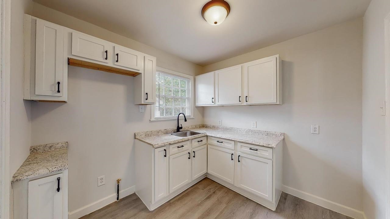 3393 Carrington Road Memphis, TN 38111 - Photo 9 of 11 Kitchen featuring white cabinetry, light wood-style flooring, and light stone countertops