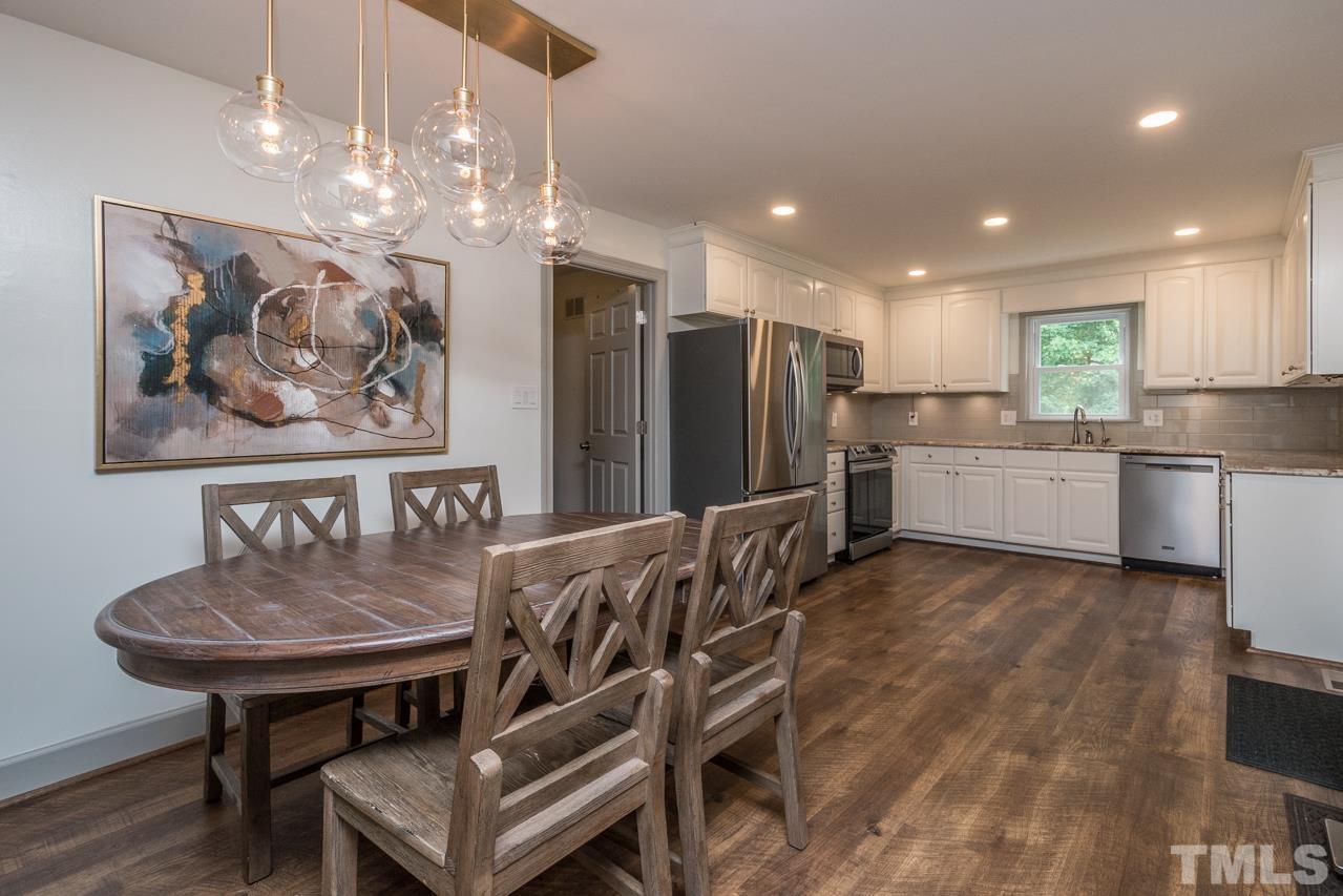 2505 Countrywood Road Raleigh, NC 27615 - Photo 7 of 36 a kitchen with stainless steel appliances kitchen island granite countertop a table chairs and a refrigerator