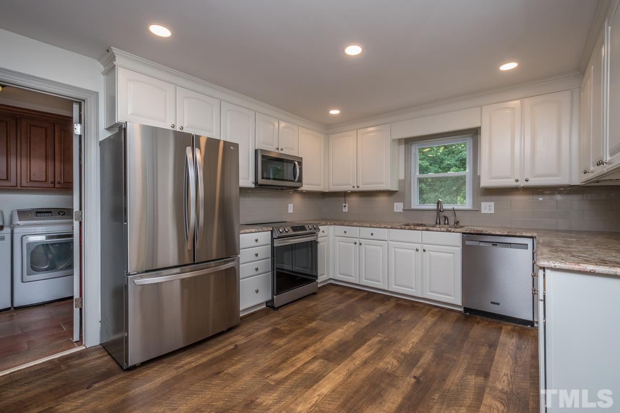 2505 Countrywood Road Raleigh, NC 27615 - Photo 8 of 36 a kitchen with granite countertop white cabinets and stainless steel appliances