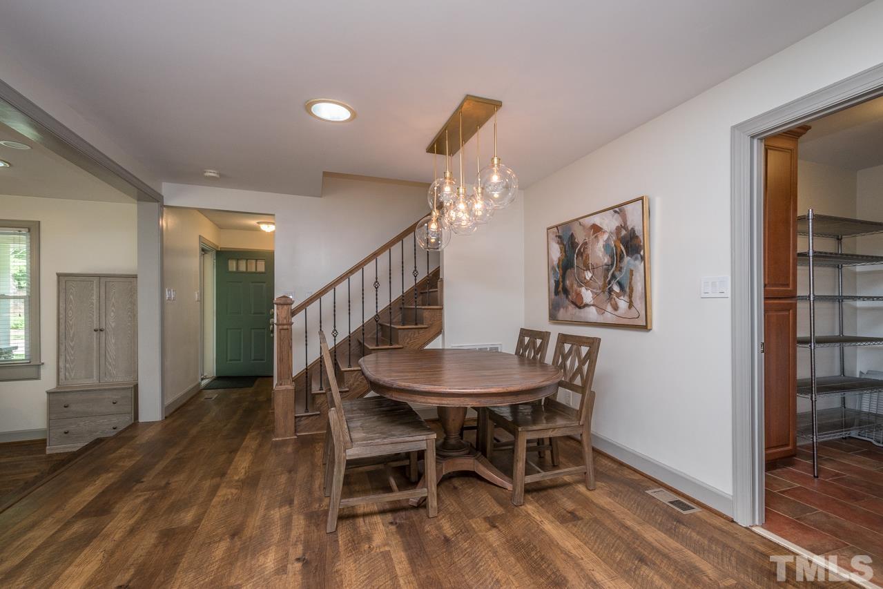 2505 Countrywood Road Raleigh, NC 27615 - Photo 10 of 36 a dining room with wooden floor a chandelier a wooden table and chairs