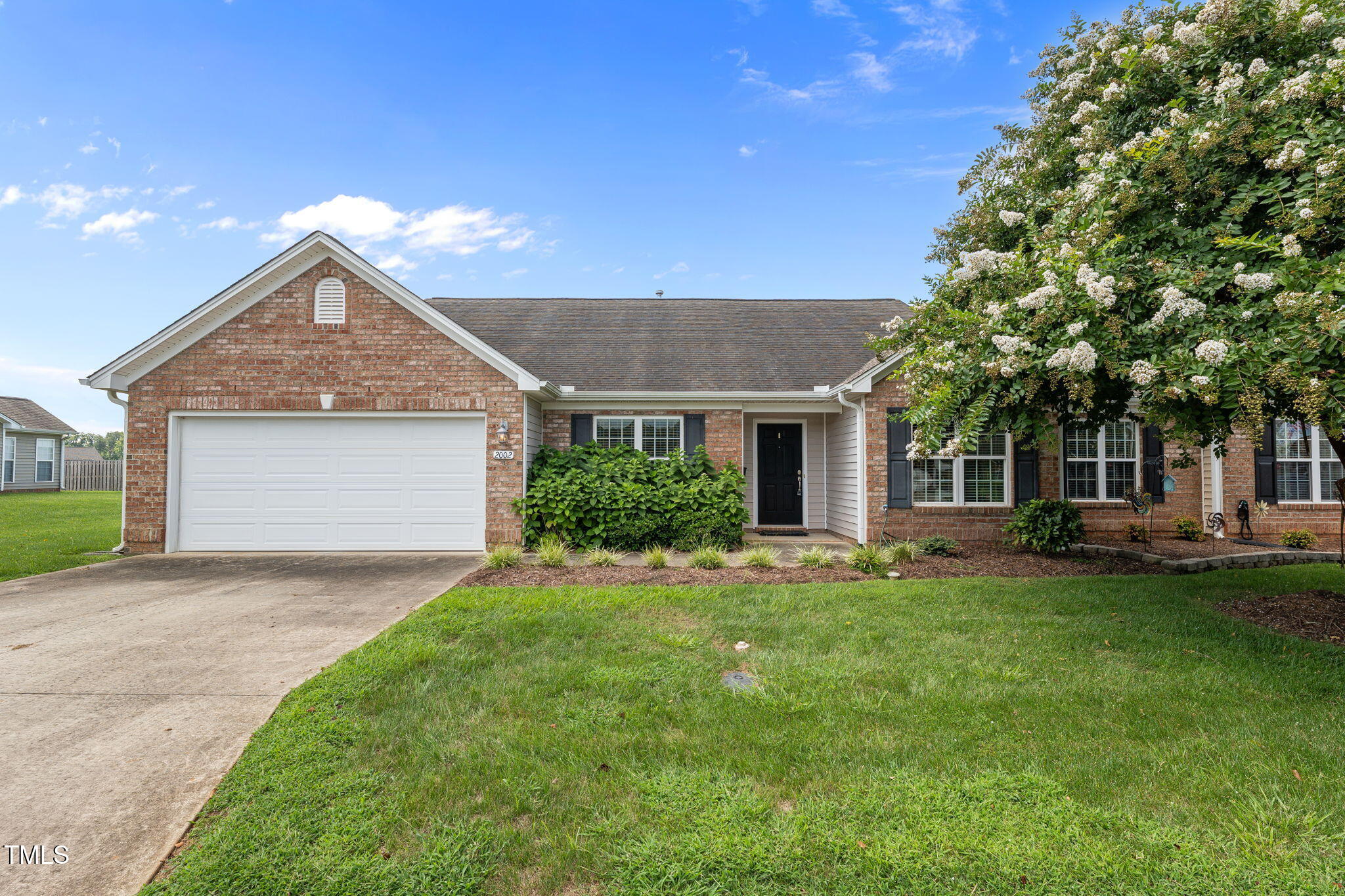 a front view of a house with a garden and trees