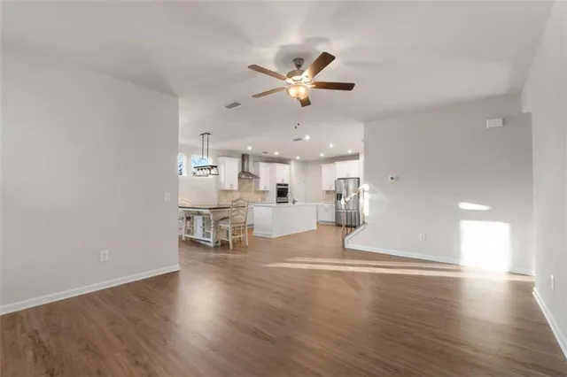 a view of a livingroom with a ceiling fan wooden floor and a ceiling fan