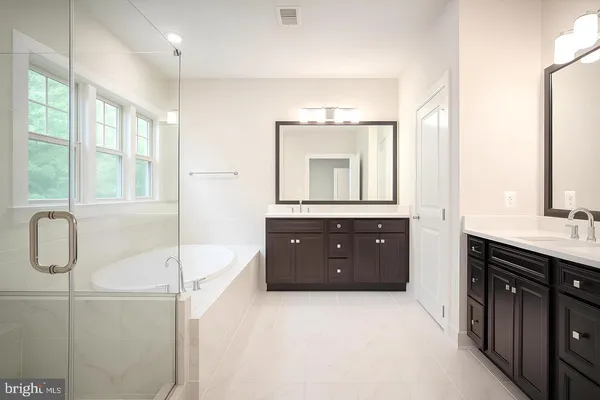a spacious bathroom with a vanity a sink a mirror a bathtub and window