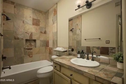 a bathroom with a granite countertop sink toilet mirror and shower
