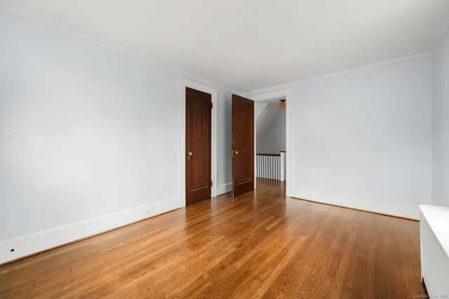 a view of an empty room with wooden floor and closet