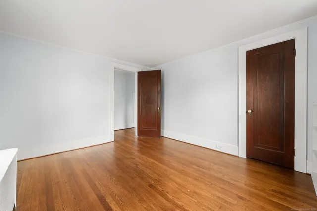 a view of empty room with wooden floor and kitchen