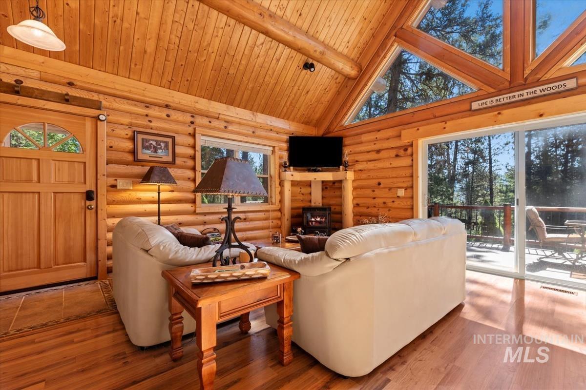 10 Elk Point Road Garden Valley, ID 83622 - Photo 12 of 42 Living area with a wood stove, hardwood / wood-style flooring, a high wood beamed ceiling, and rustic walls