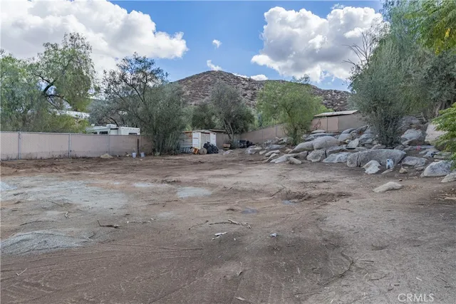 a view of a dry yard with wooden fence