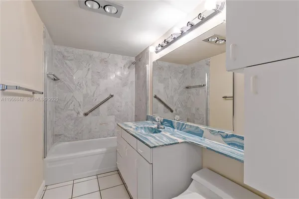 a bathroom with a granite countertop sink a mirror and a bathtub with shower