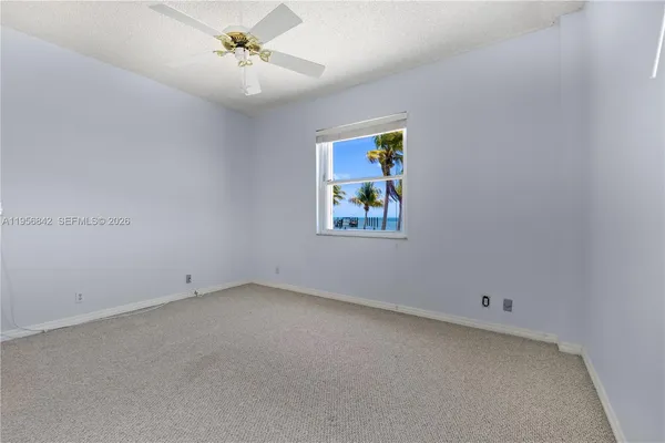 an empty room with a ceiling fan and window